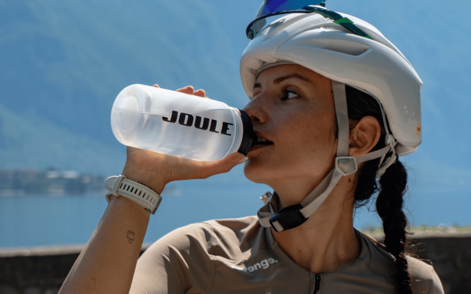 Ragazza con borraccia Joule si idrata durante un tour in bici da corsa